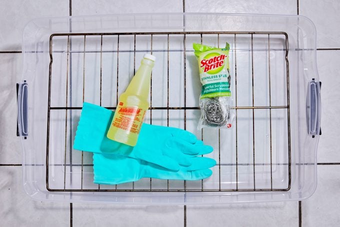 oven rack and cleaning supplies laid out in a plastic tub