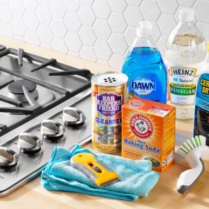 Cleaning supplies arranged next to a gas stove in a kitchen