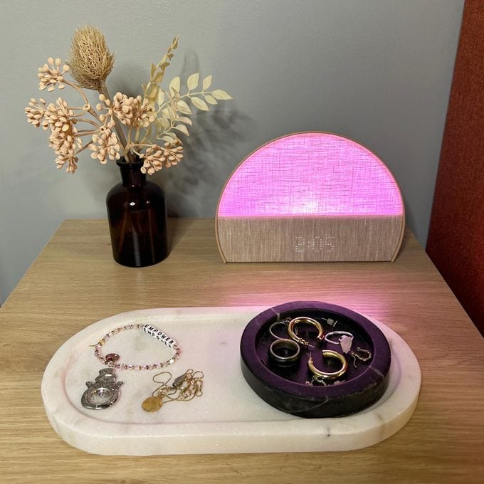 Sunrise Clock glowing pink on a bedside table