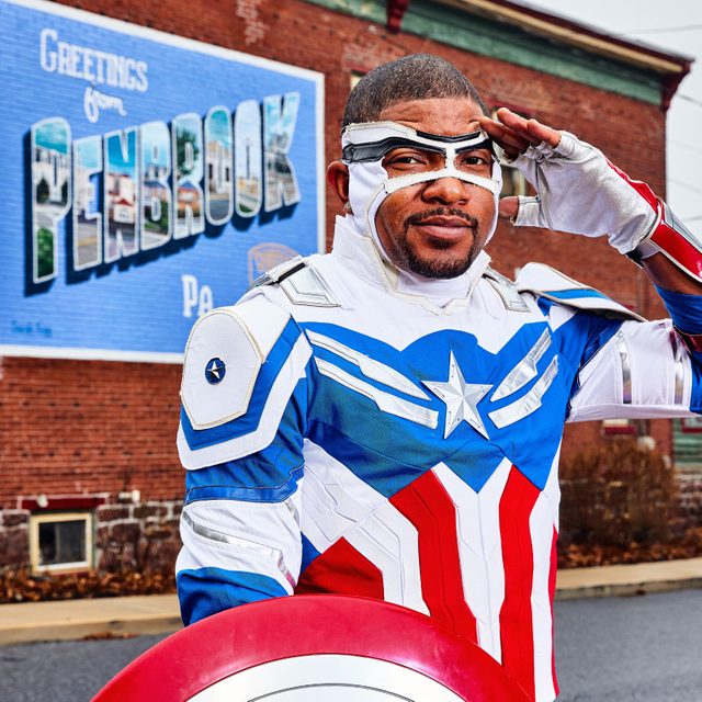Timothy White Jr. in a Captain America costume standing in front of a Penbrook, PA mural