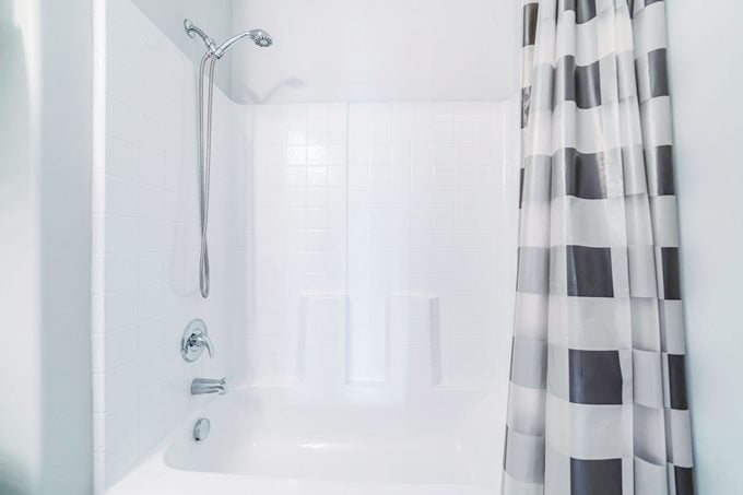 fiberglass shower tub in a bathroom with open shower curtain