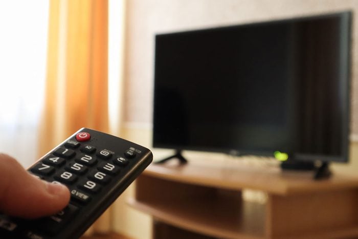Hand Holding A Television Remote Control And Surfing Programs On Television