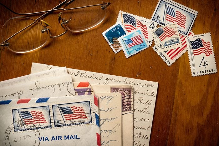 Letters With American Flag Postage Stamps On Table and reading glasses