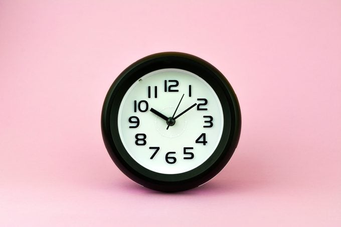 Black and white alarm clock on pink background.