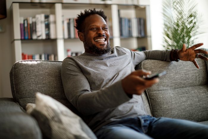 man watching tv in living room and laughing