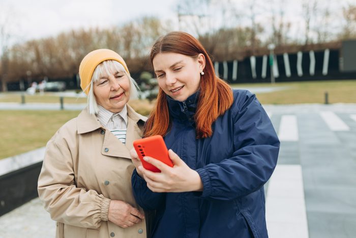 Womens use smartphone to find what they are interested in outdoors. Searching information data on internet, networking concept. Friends watching videos on a smartphone