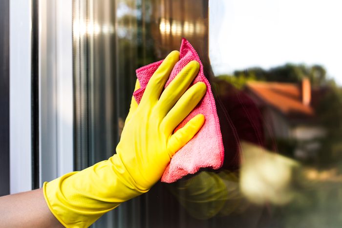 A man's hand with protective glove cleaning the glass window pane