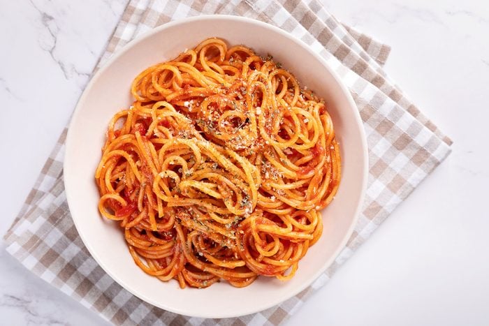 Spaghetti with tomato sauce on white background.