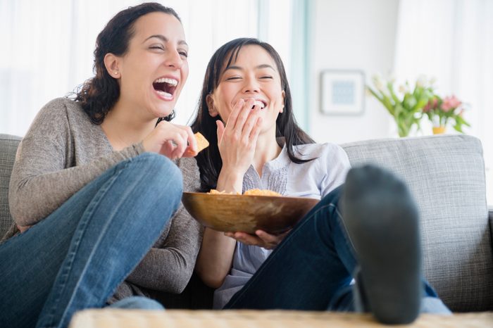 Women laughing on sofa together watching a funny movie
