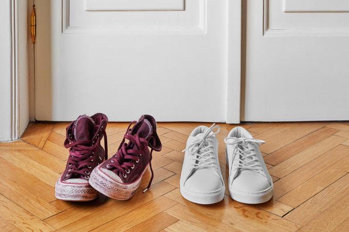Old and new shoes by the front door on a hardwood floor