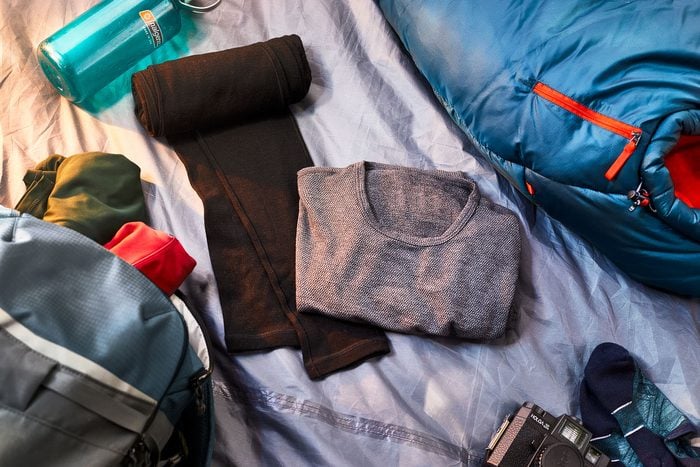 Merino wool top and leggings inside a tent with sleeping back and other supplies nearby