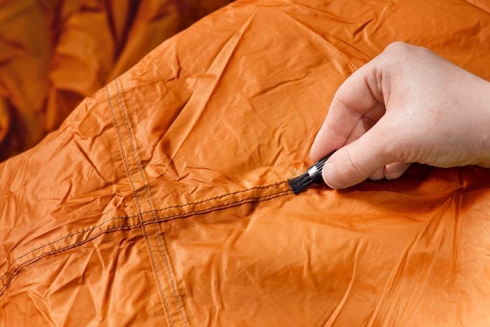 hand applies seam waterproofing to a tent seam with a small applicator brush