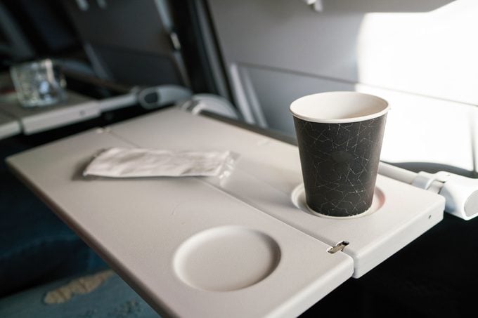 Cup Rests on Lap tray on the back of a passenger seat of a commercial airplane