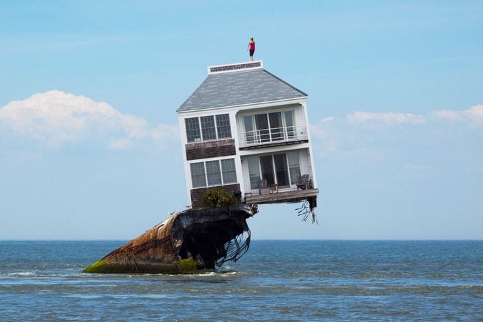 House Perched Above the water slanted on a rock