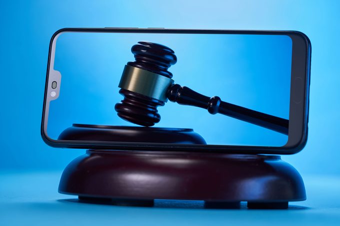 Gavel Hammer on a Smartphone Screen On Blue Background.