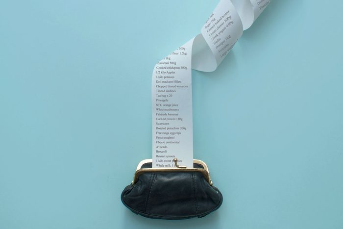 Large receipt coming out of black coin purse on a blue background