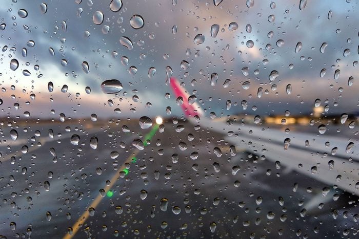 Blurry View Of An Airport Runway Through An Airplane Window With Rain Drops