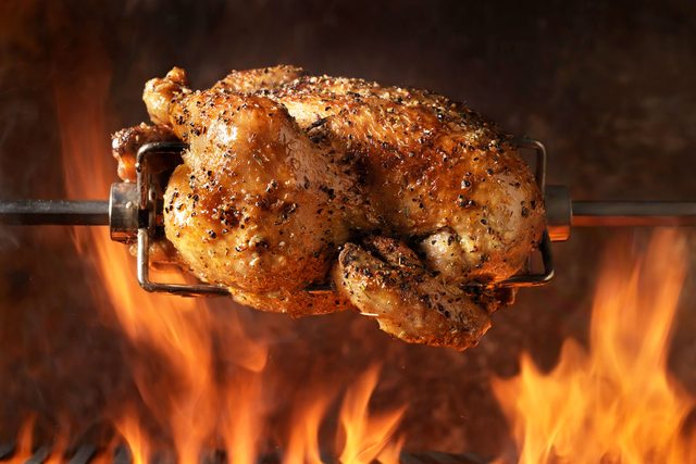 Rotisserie Chicken On The Bbq above an open flame 