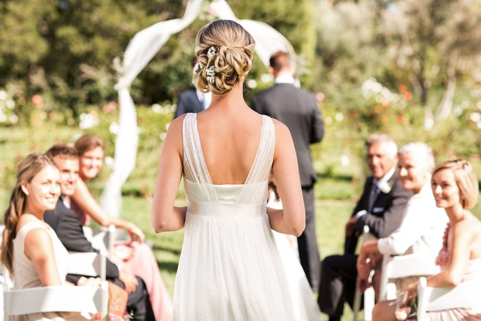 Rear view of young bride walking down the aisle while guests looking at her during wedding ceremony