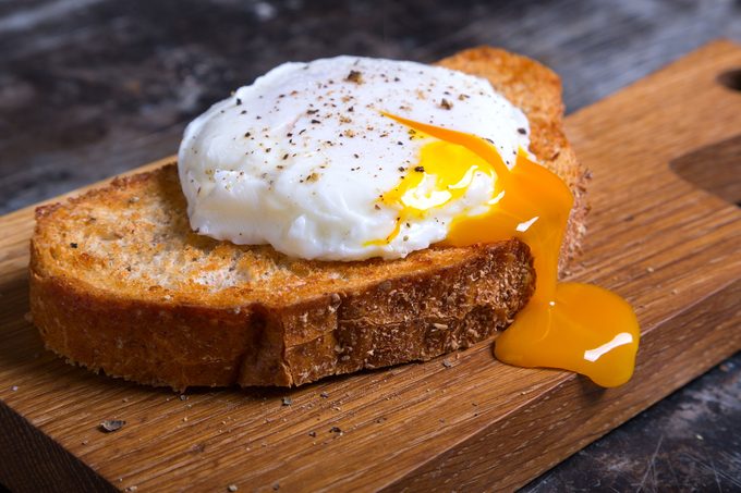 Poached Egg on Toast on a wooden butcher block cutting board