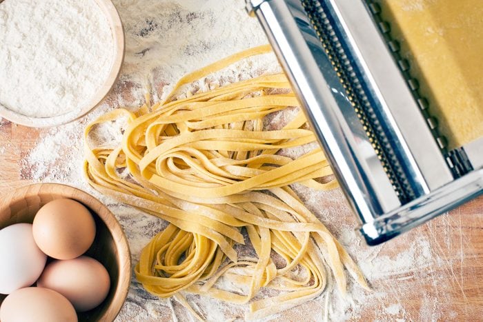 fresh pasta, eggs, flour and pasta machine on kitchen table