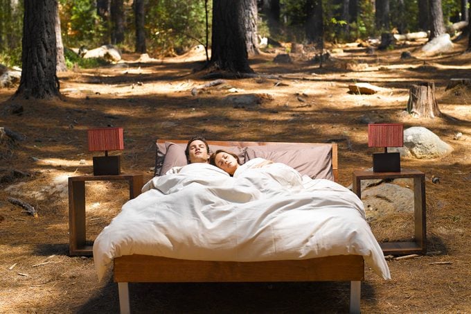 A Couple Sleeping In A Bed Outdoors In The Woods