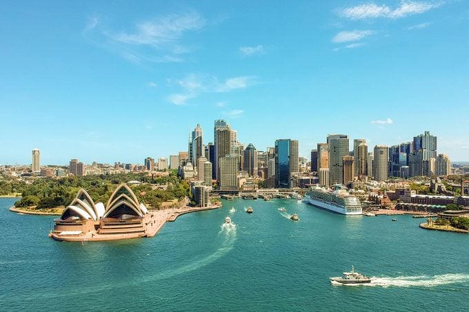 aerial drone view of the Sydney Harbour with the Opera House, a cruise ship and many skyscrapers in the background
