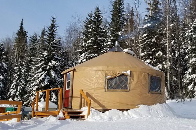 Small Circular Housing, a Yurt, in a Snowy Evergreen Setting