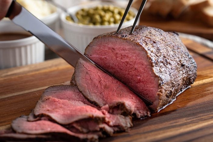 slicing eye of round roasted beef with knife