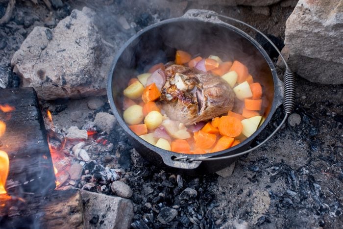 Dutch oven campfire cooking process - lamb and vegetables in a cast iron camp oven, Camping life