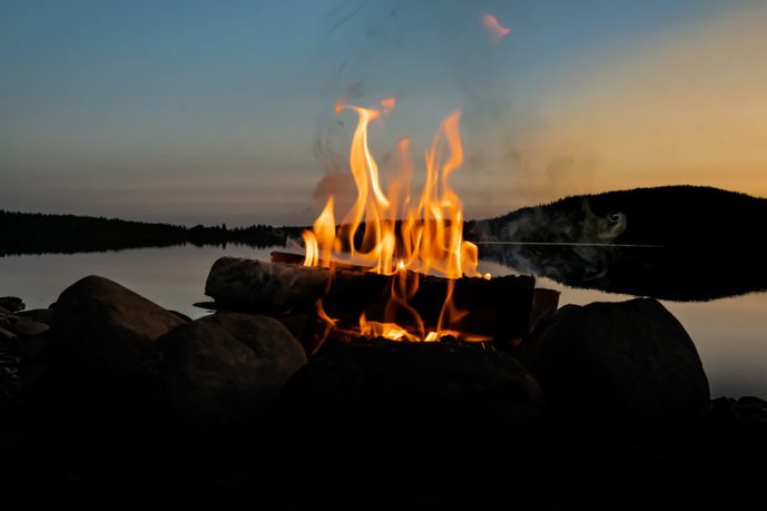 Cozy camp fire on the beach of a lake in the evening.