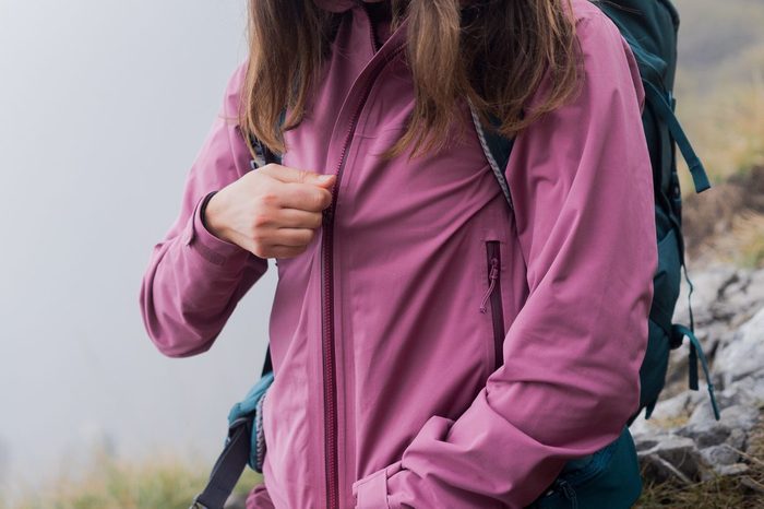 Female hiker zips rain jacket up, as the fog rolls in