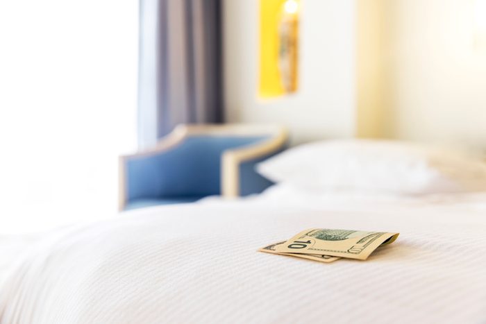 Traditional tips is laying on the corner of bed in hotel room for room cleaner
