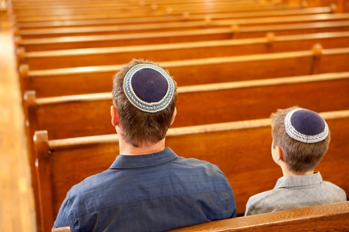 Father and son in yarmulkes sitting in synagogue