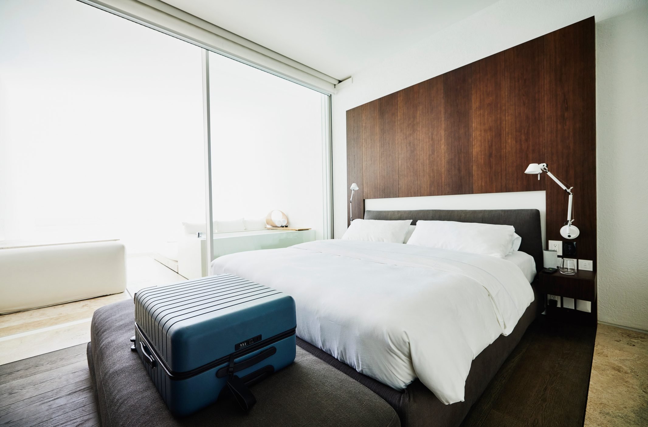 Wide shot of suitcase at end of bed in luxury hotel room