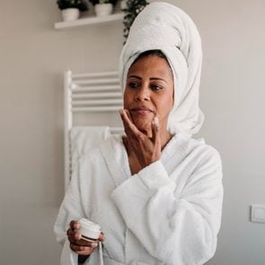 Woman applying face cream in bathroom