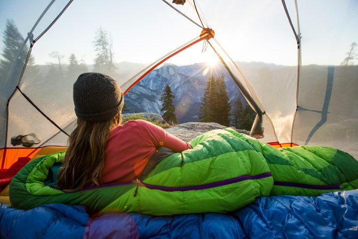 A woman watching sunrise from a tent.