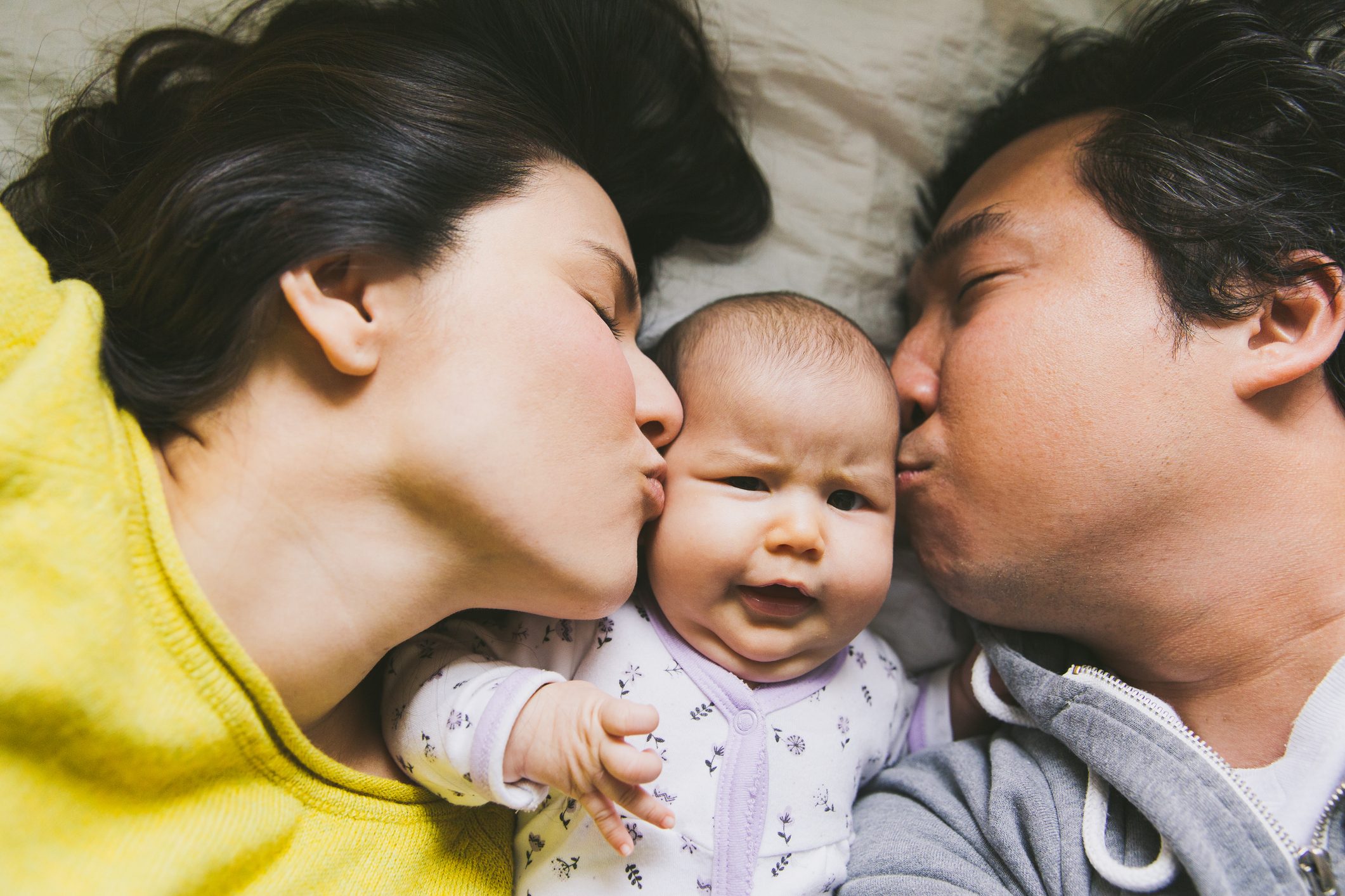 Parents kissing baby