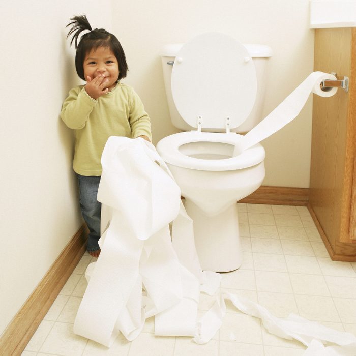 Female toddler unrolling toilet paper