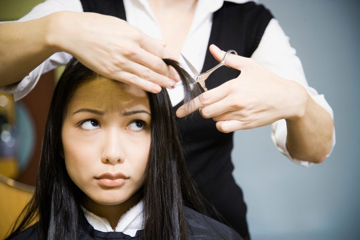 Female hair stylist cutting woman's hair in salon