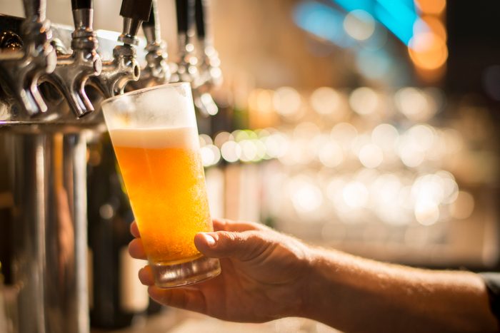Cropped hand of bartender filling beer from tap at bar