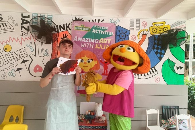 boy posing with sesame street characters and a drawing