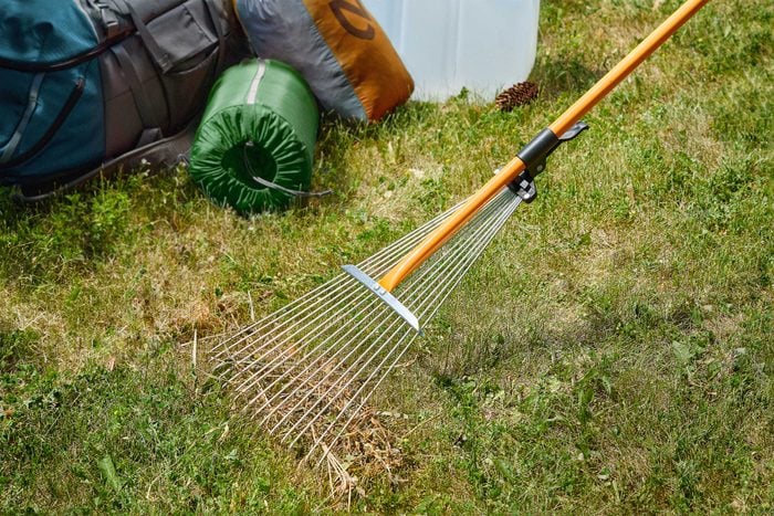 Metal rake clearing the ground near camping supplies