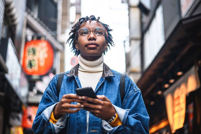 Young African female traveler attempting to find her way through the streets of urban Tokyo with a smartphone