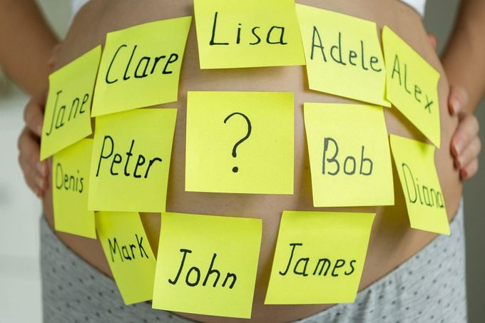 Closeup Of Pregnant Woman With Child Names On Memo Stickers on her belly