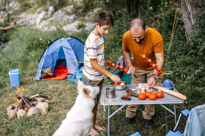 Son and dad making lunch in nature