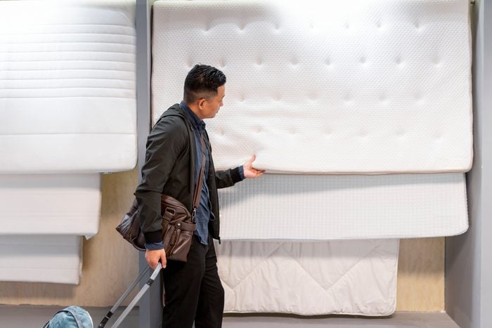 Asian man choosing for mattress while shopping