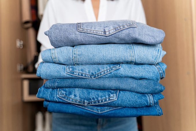 Woman holding stack of blue jeans