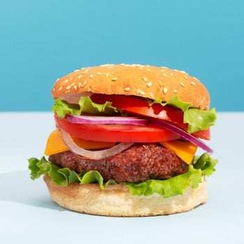 Fresh juicy beef hamburger with french fries placed on blue creative trendy background