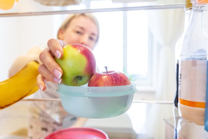 Vegetarian healthy food, apple diet for women. Storing food in the refrigerator in a plastic container